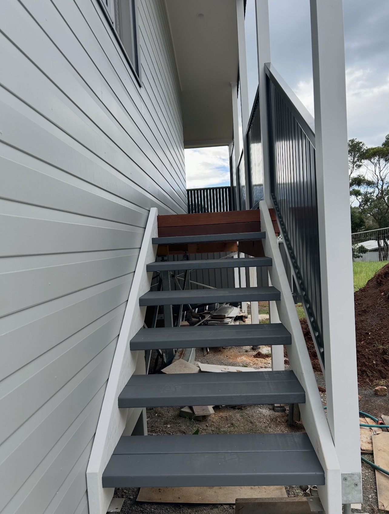 External staircase with fresh grey treads and white weatherboard cladding