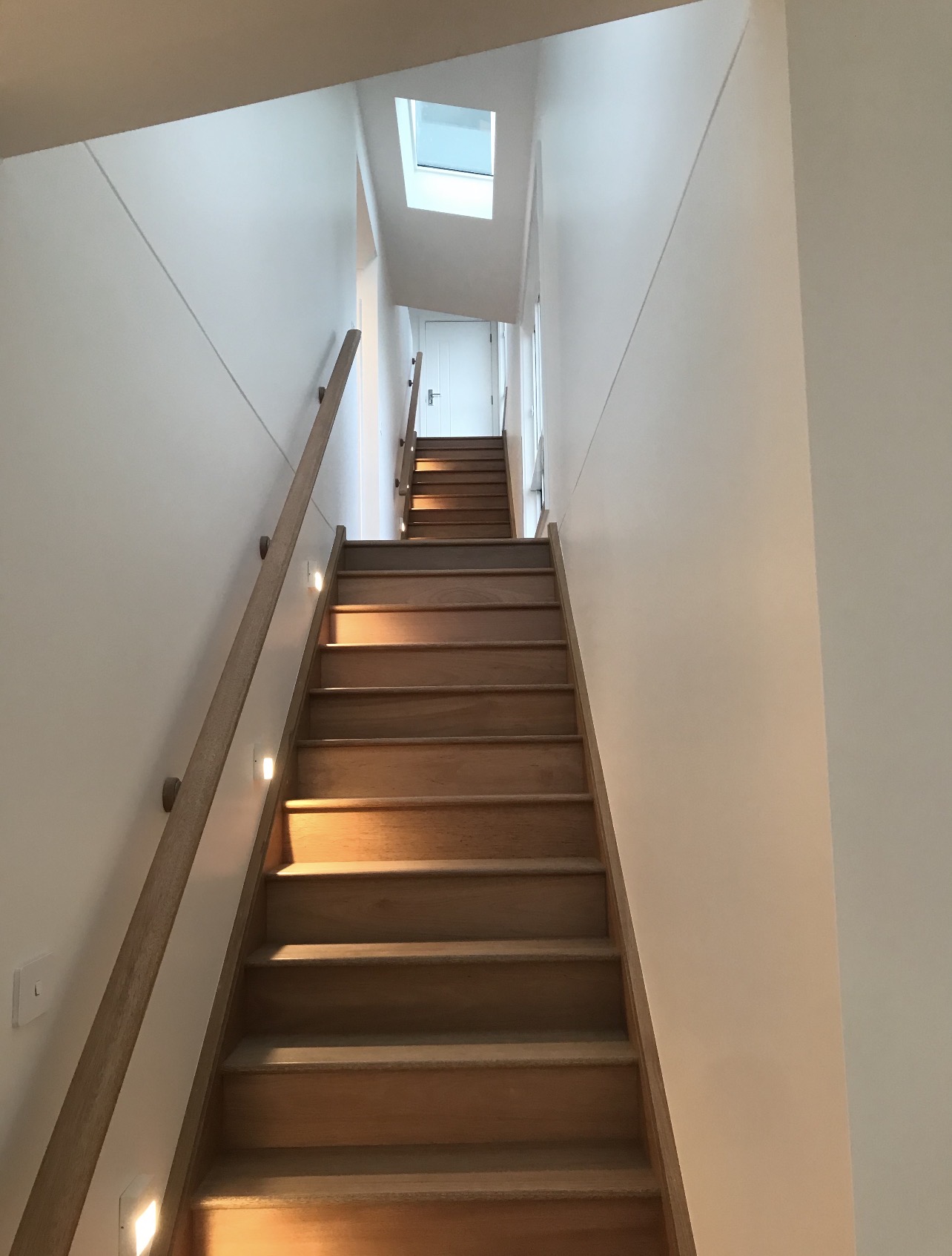 Interior stairwell with fresh white walls, timber treads and skylight above