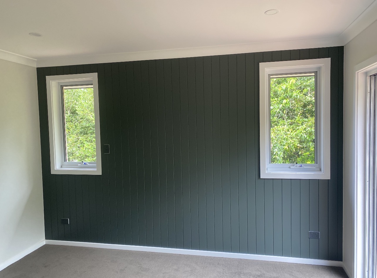 Dark green vertical panelled feature wall between two windows