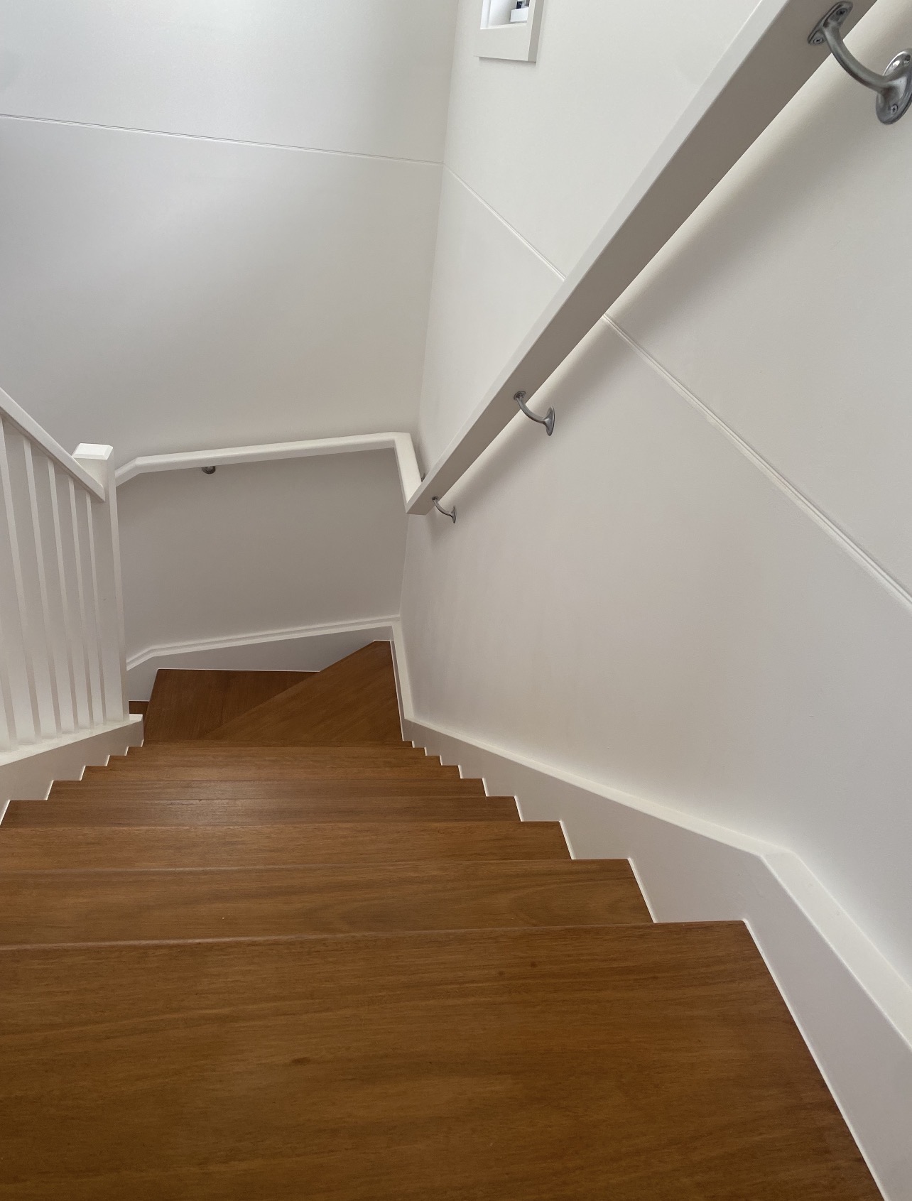 Painted stairwell looking down onto polished timber steps and white balustrade